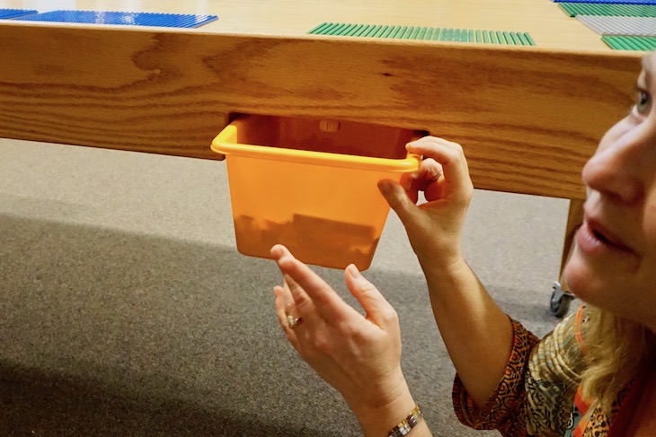 <p>Smart! The builders included a wooden stop to ensure AGS students can’t drop the LEGO tubs installed on each side of the table.</p>
